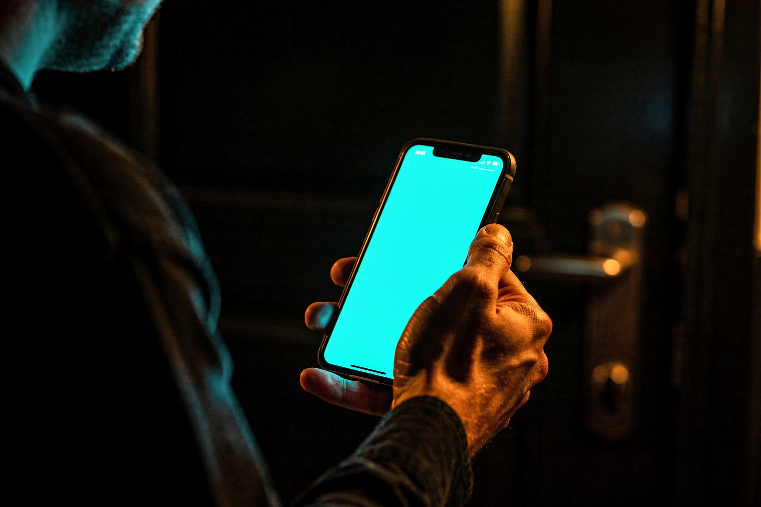 Personne appelant un serrurier devant sa porte, ecran du telephone allume